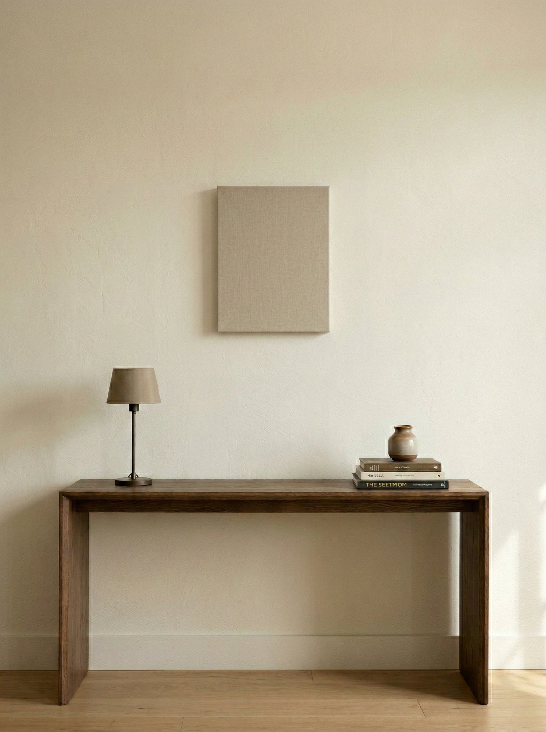 Wooden console table with a lamp and books against a beige wall