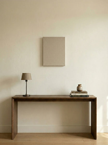 Wooden console table with a lamp and books against a beige wall